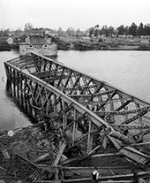 Vernielde brug over de Maas bij Roermond, 1945. Het Nederlandse vaarwegennet kwam zwaar gehavend uit de Tweede Wereldoorlog tevoorschijn. Opgeblazen en stukgeschoten bruggen, defecte sluizen, mijnen en scheepswrakken versperden op veel plaatsen de doorvaart. Eind 1945 waren alle hoofdroutes opnieuw bevaarbaar, hoewel op veel plaatsen met ernstige belemmeringen.