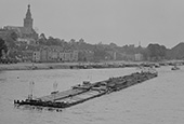 Duwvaartproeven, circa 1960. De duwboot <em>Wasserbüffel</em> met vier duwbakken en twee sleepschepen in opvaart op de Waal bij Nijmegen. Deze foto dateert uit de beginperiode van de duwvaart. Omdat er toen nog onvoldoende duwbakken waren, werd bij de proeven gebruikgemaakt van sleepschepen.