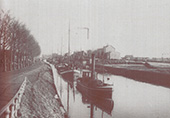 Stoomboot met minstens vier sleepschepen op het Hoendiep bij Groningen, circa 1925. Het Hoendiep vormde de hoofdroute voor het vervoer van en naar de provincie Groningen. Op de vaarroute van Groningen naar Lemmer moesten talrijke obstakels, zoals smalle, ondiepe vaarwateren, krappe sluizen en ochten, worden gepasseerd.