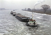 IJsbreker met sleepschepen op de Bergse Maas, 1997. Bij strenge winters vriezen de vaarwegen dicht. De scheepvaart wordt dan gaande gehouden met ijsbrekers, die de vaarweg ijsvrij maken voor andere vaartuigen. Soms hebben ze andere schepen op sleeptouw. Soms varen die op eigen kracht door de vrijgemaakte vaargeul.